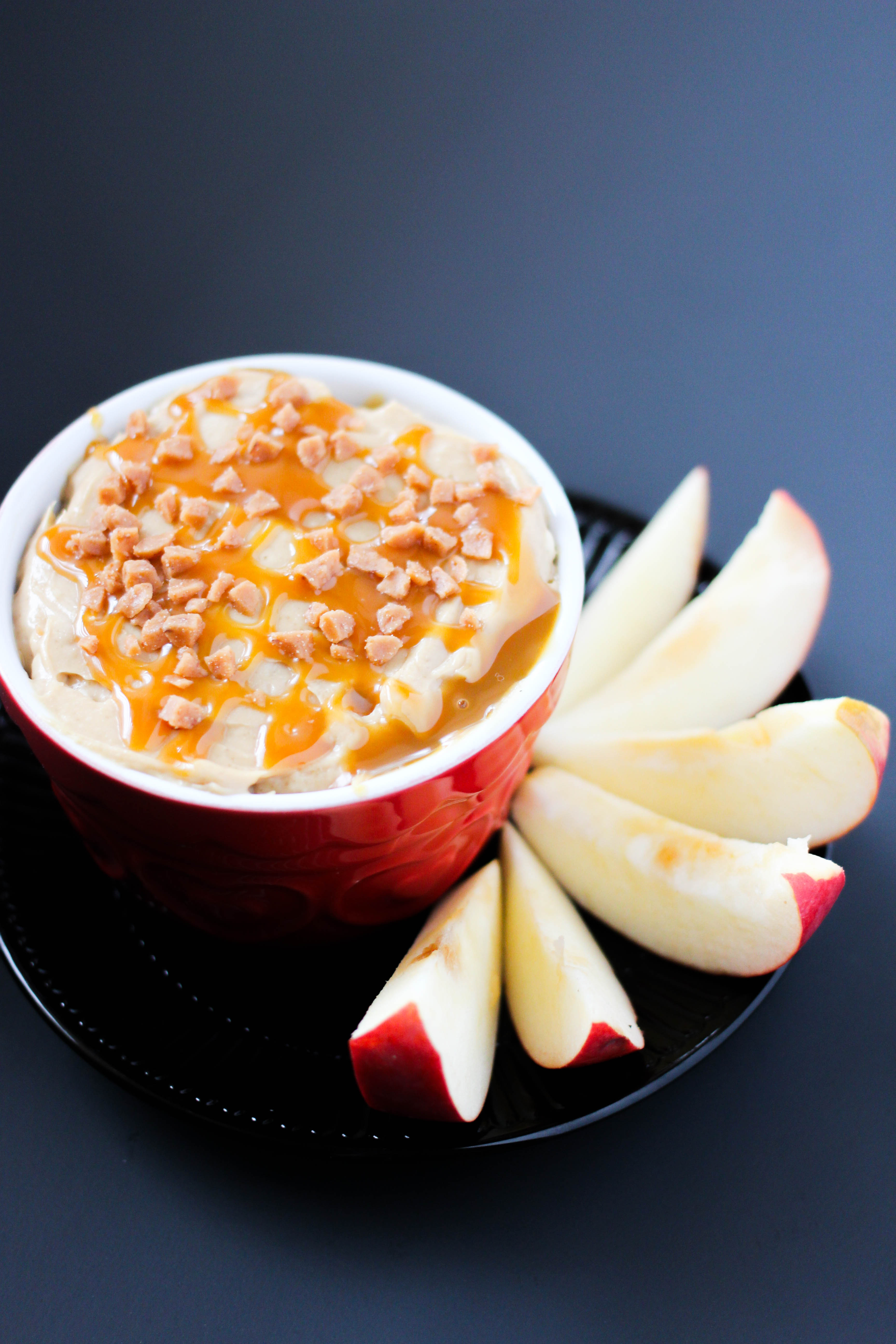 caramel apple dip on a black plate with apples