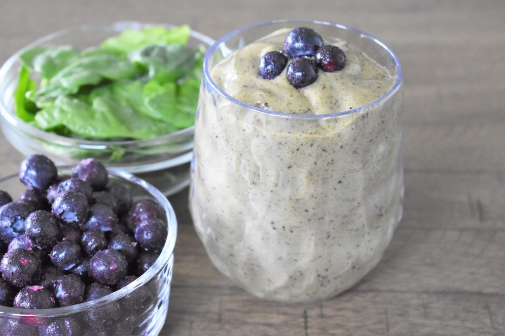 Green Spinach Smoothie with blueberries and spinach on the side.