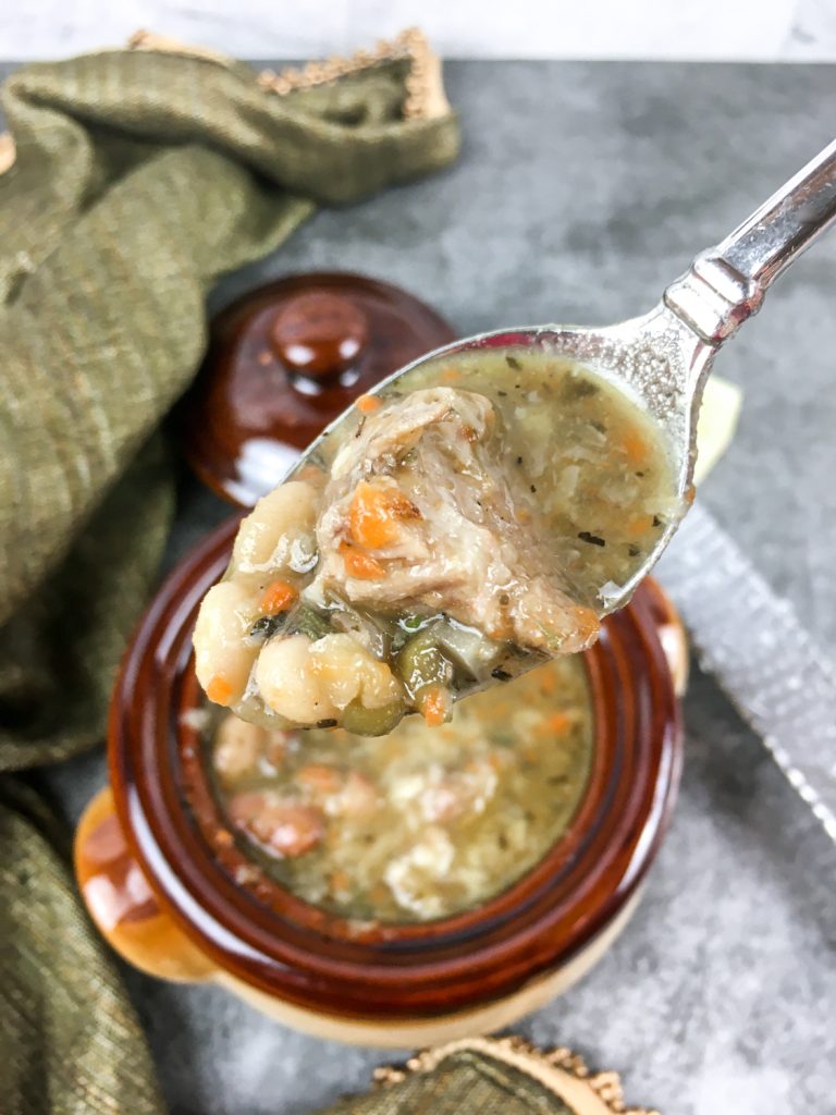 A spoon lifting up some of the soup out of a bowl.