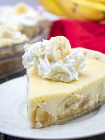 A slice with whipped cream and bananas on top.